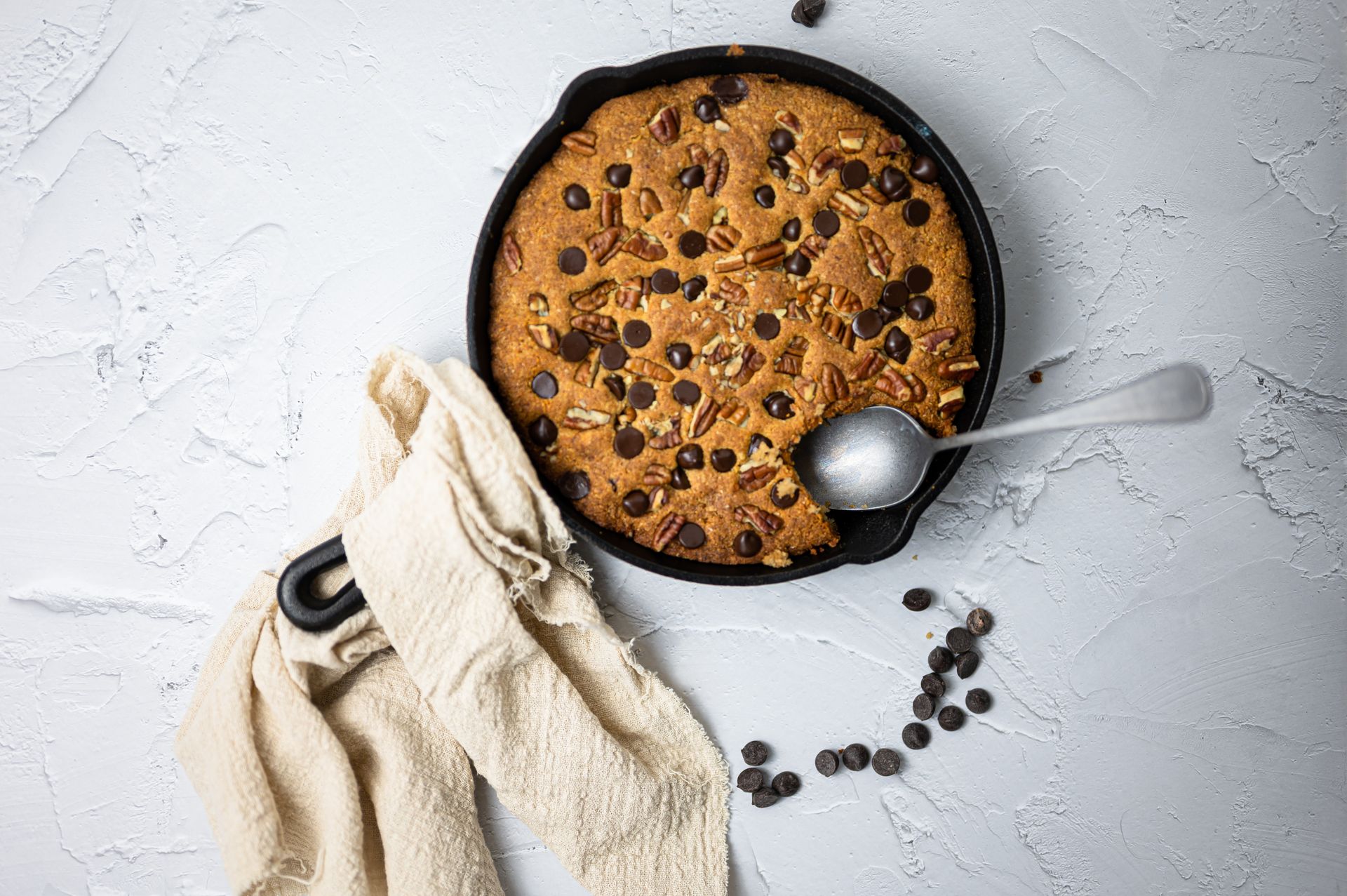 Delicious homemade cookie with chocolate chips and nuts in a cast iron skillet, perfect for dessert lovers.