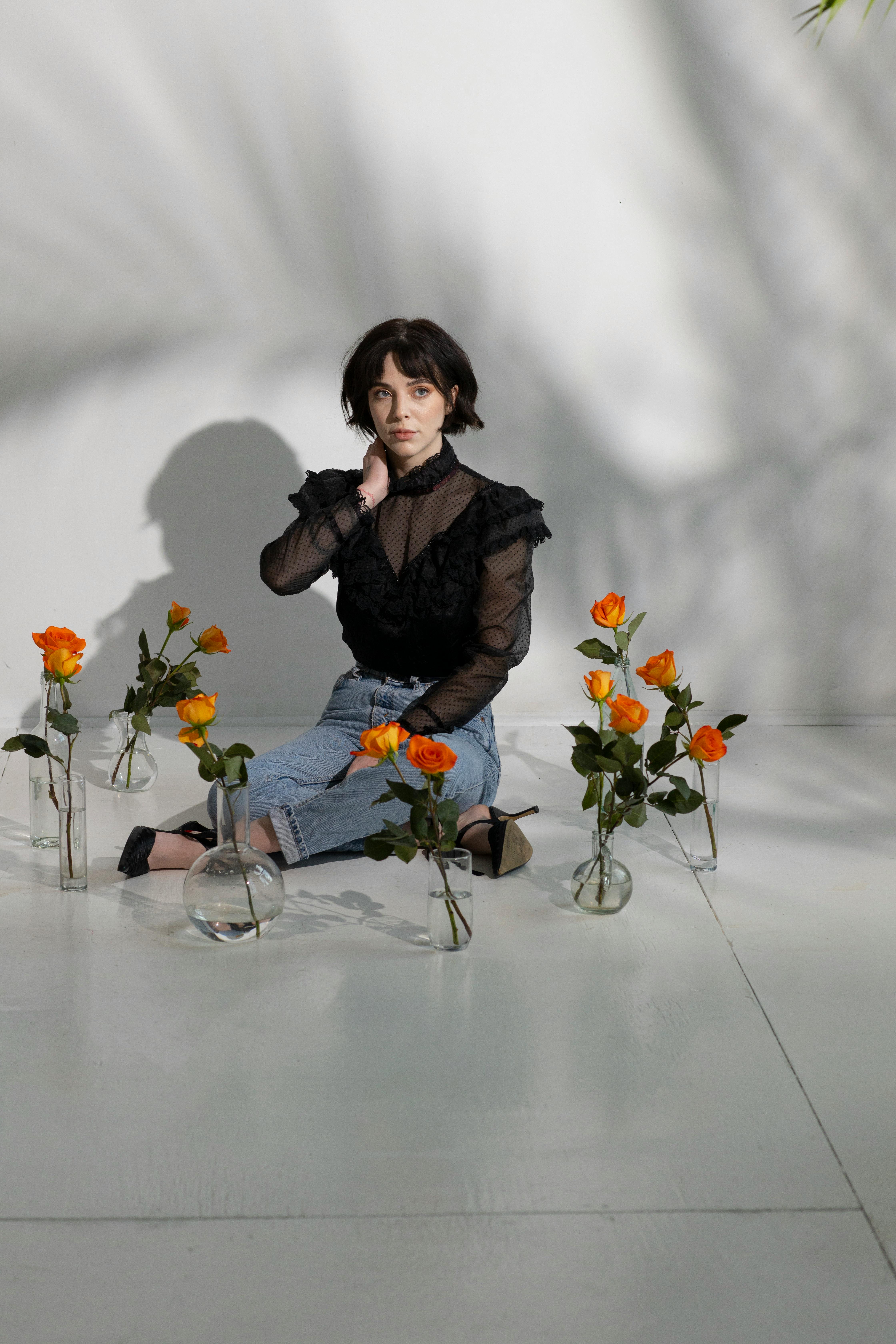 woman on floor among vases with flowers