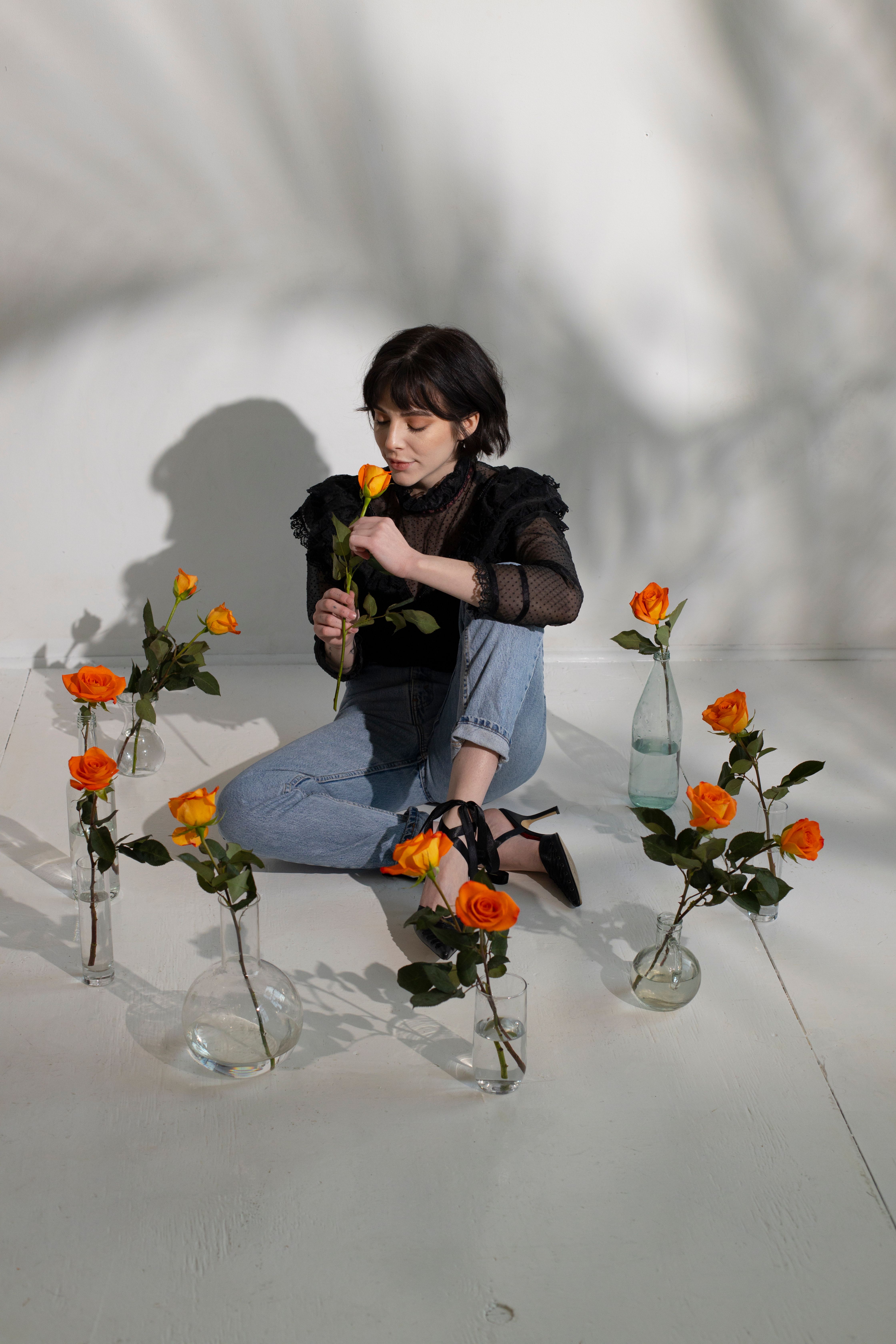 Woman on floor surrounded with vases with roses · Free Stock Photo