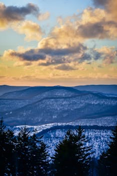 Breathtaking view of snow-capped mountains under a vibrant sunset sky with clouds.