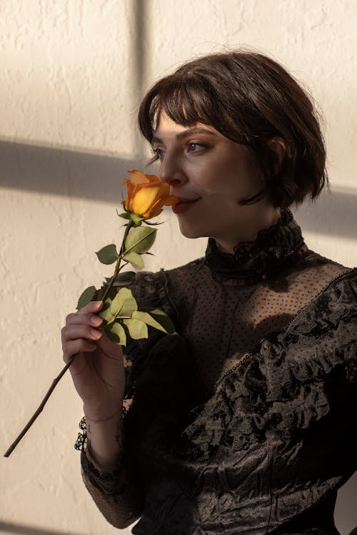 A Woman Smelling a Yellow Rose
