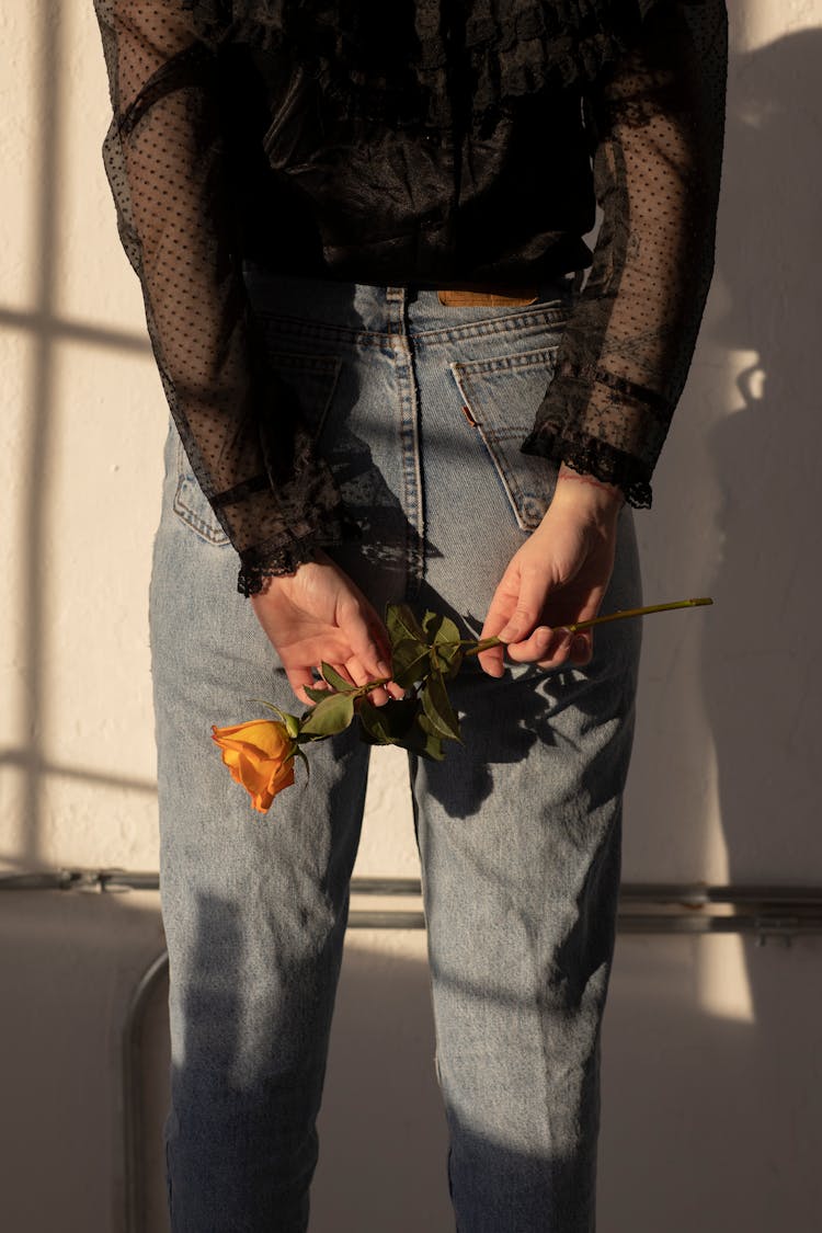 Woman Holding An Orange Rose Behind Her Back 