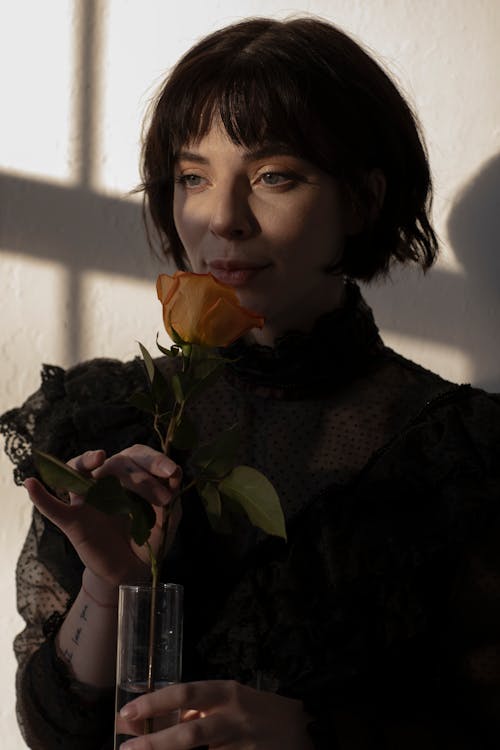 A Woman in Black Long Sleeve Shirt Holding an Orange Flower