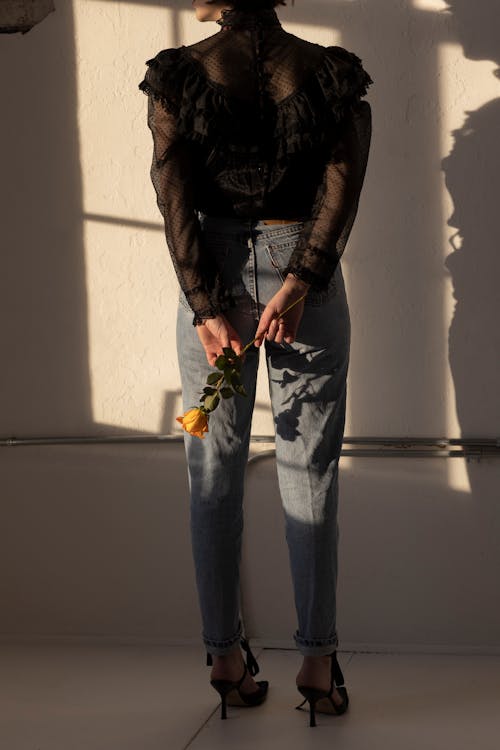 A Person in Denim Jeans Holding a Flower