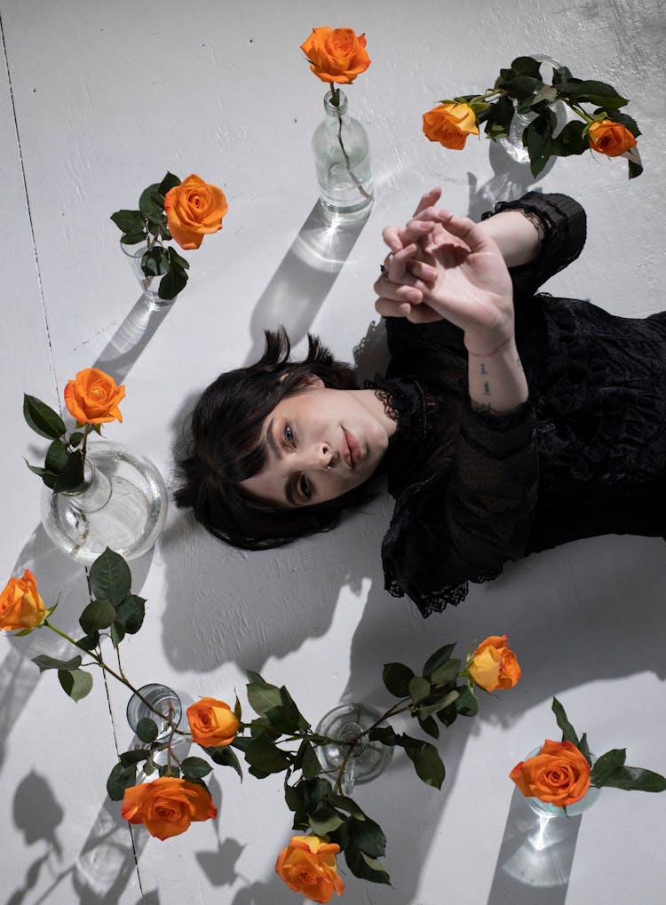 Calm Gothic Woman Among Vases With Orange Roses