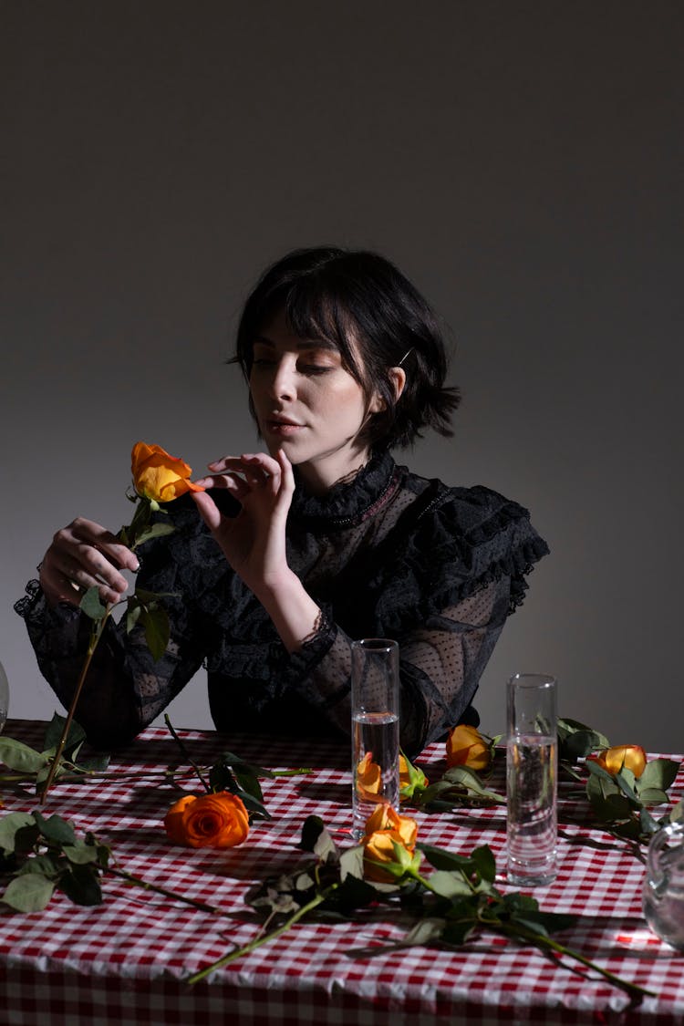 Woman In Black Outfit Touching Gentle Petals Of Orange Rose