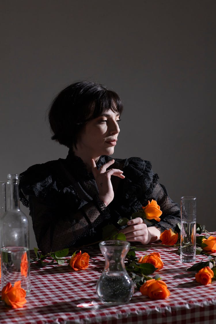 Dreamy Gothic Woman At Table With Glassware And Blooming Roses