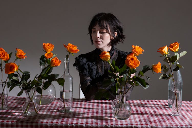 Gothic Thought Woman In Black Blouse At Table With Roses