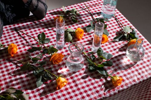 Free From above of crop anonymous female at table with glass transparent vases with water and roses Stock Photo
