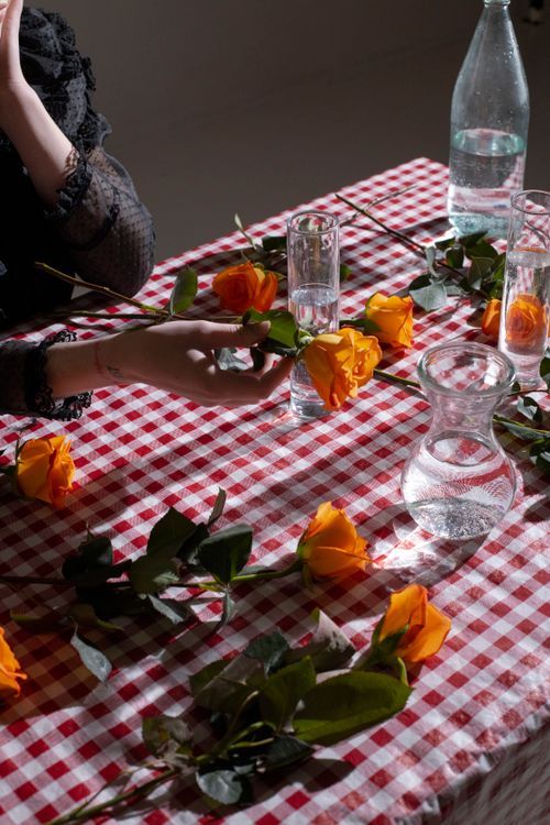 Free From above of crop anonymous female at table with glass vases with water on gray background Stock Photo