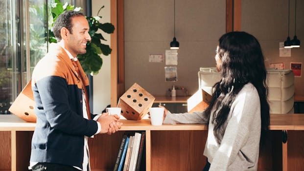 Two colleagues engaging in a casual conversation over coffee in an office setting.