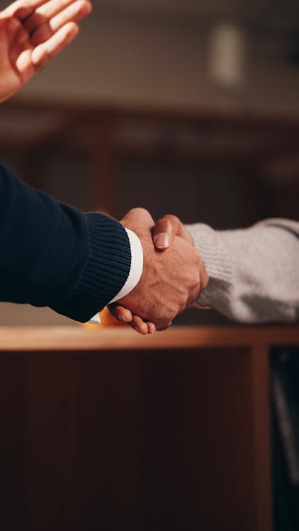 An investor shaking hands with a lender in front of rental properties