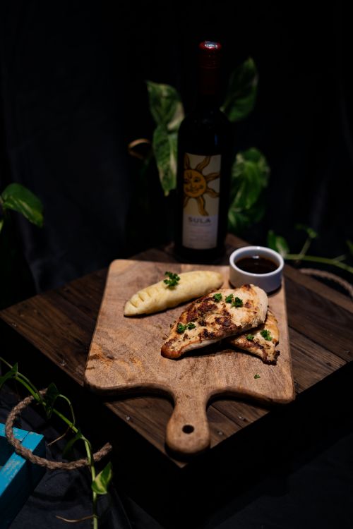 Free A rustic presentation of pastries with a bottle of wine on a wooden board, shot in low light. Stock Photo