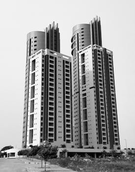 A striking grayscale image of twin modern skyscrapers set against a clear sky.