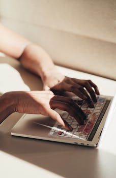 A close-up shot of hands typing on a laptop keyboard, highlighting productivity and technology.