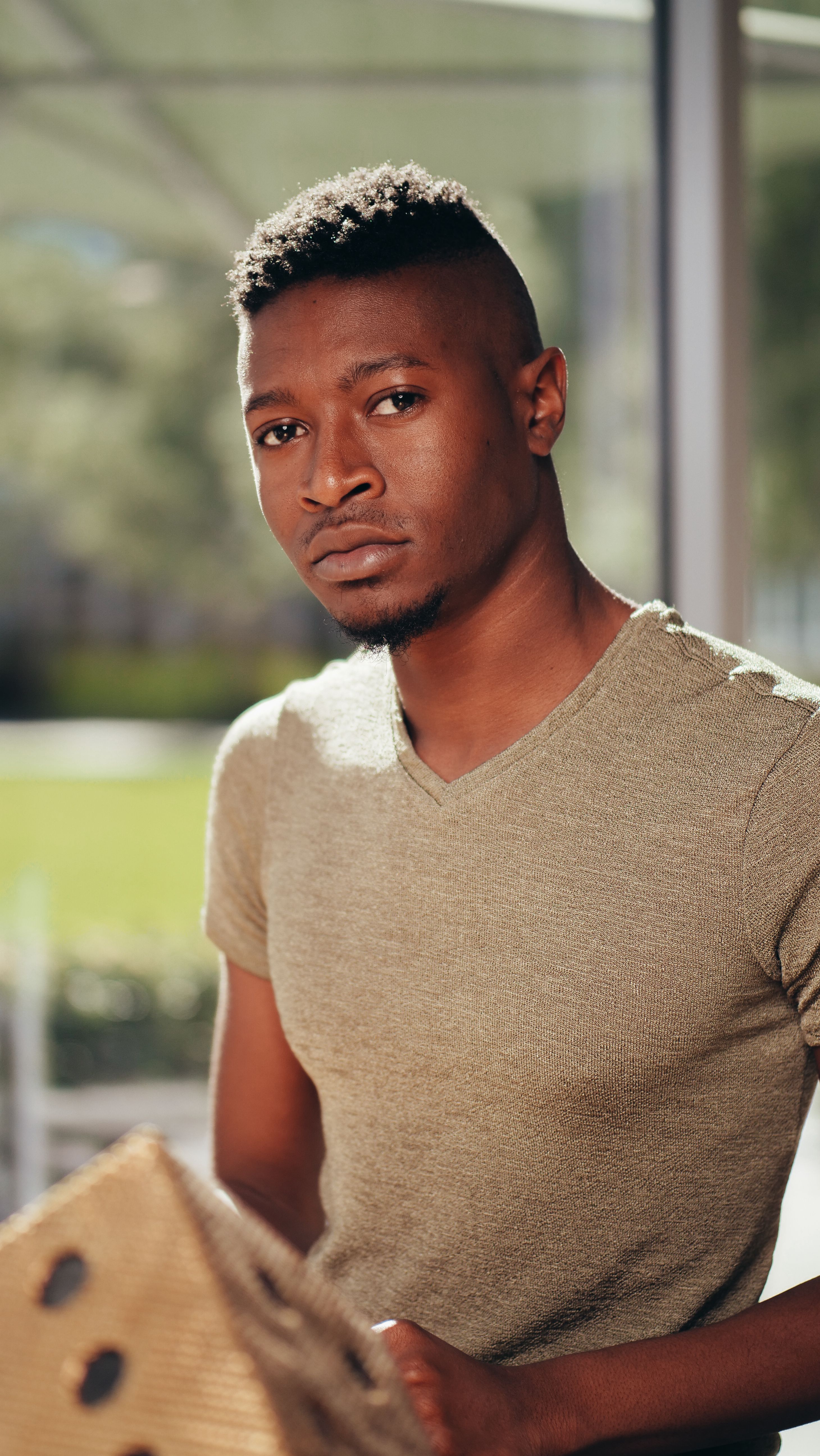 Portrait of a handsome young black man posing outdoors in natural sunlight, showcasing modern fashion.