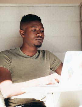 Young man working diligently on a laptop in a well-lit indoor setting.