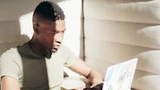 A Man in Gray Shirt Looking at the Laptop