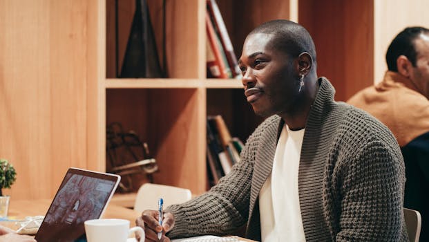 African American man working in a cozy office setting with a laptop and notepad.