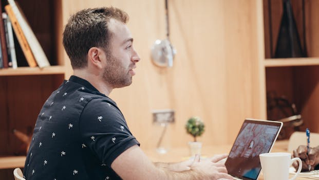 Young man with laptop working in a cozy office space, focused on tasks.