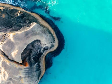 Stunning aerial view showcasing a unique rock formation surrounded by vibrant blue water.