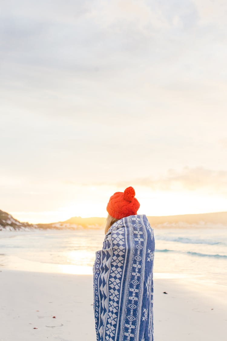 Woman Wrapped In A Blanket On A Beach