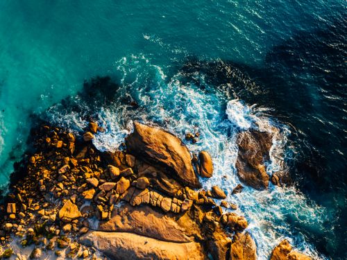 Free Vibrant aerial shot of a rocky coastline with waves crashing, showcasing nature's beauty. Stock Photo