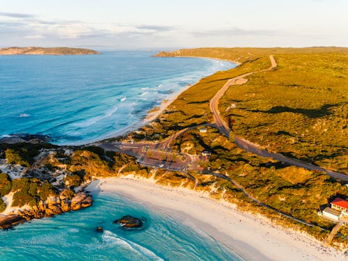 Free Stunning aerial view of a coastline with a sandy beach and turquoise sea during sunset. Stock Photo