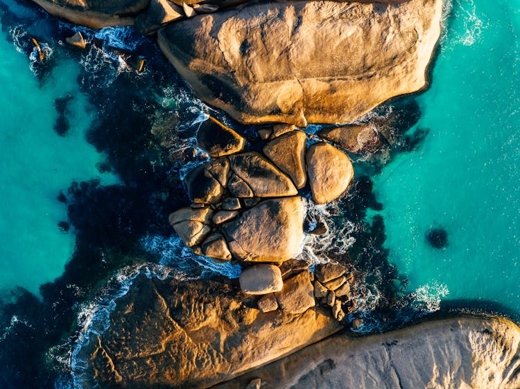 Aerial View Of Ocean Waves Crashing On A Rock Formation
