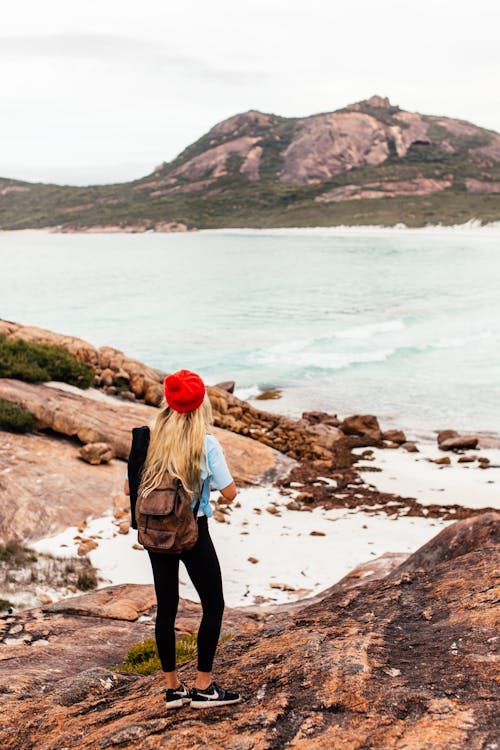 Free A Woman with a Backpack Standing next to a Lake Stock Photo