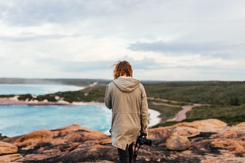 Free A photographer stands on a cliff overlooking a stunning coastal view. Stock Photo