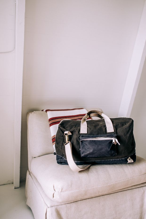 Waxed canvas weekender bag resting on a pale linen chair, photo by Rachel Claire on Pexels