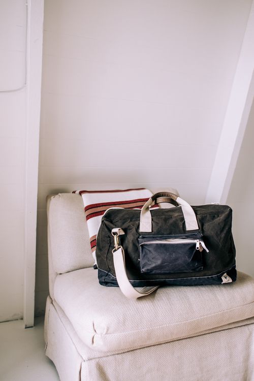 Free Chic black leather bag on a soft linen sofa, ideal for travel and fashion themes. Stock Photo