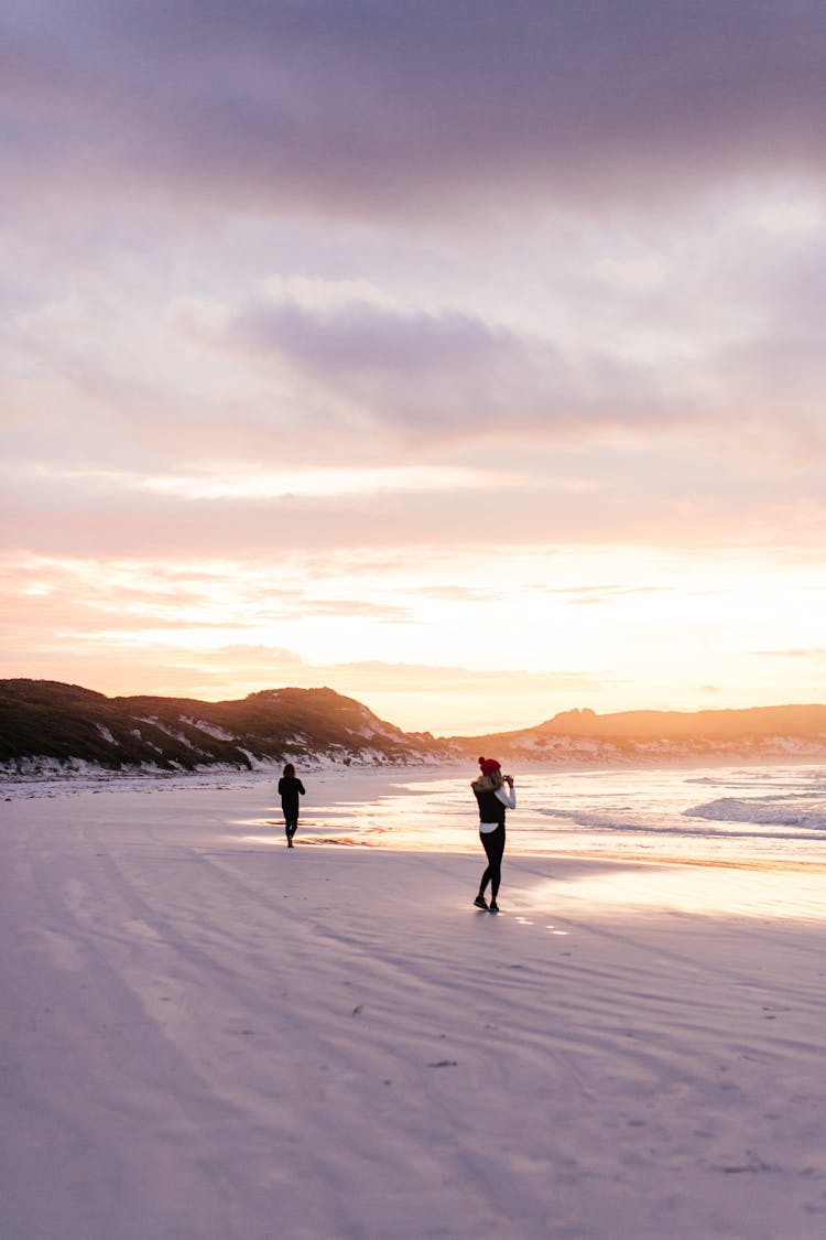 People Walking On A Beach At Sunset In Winter