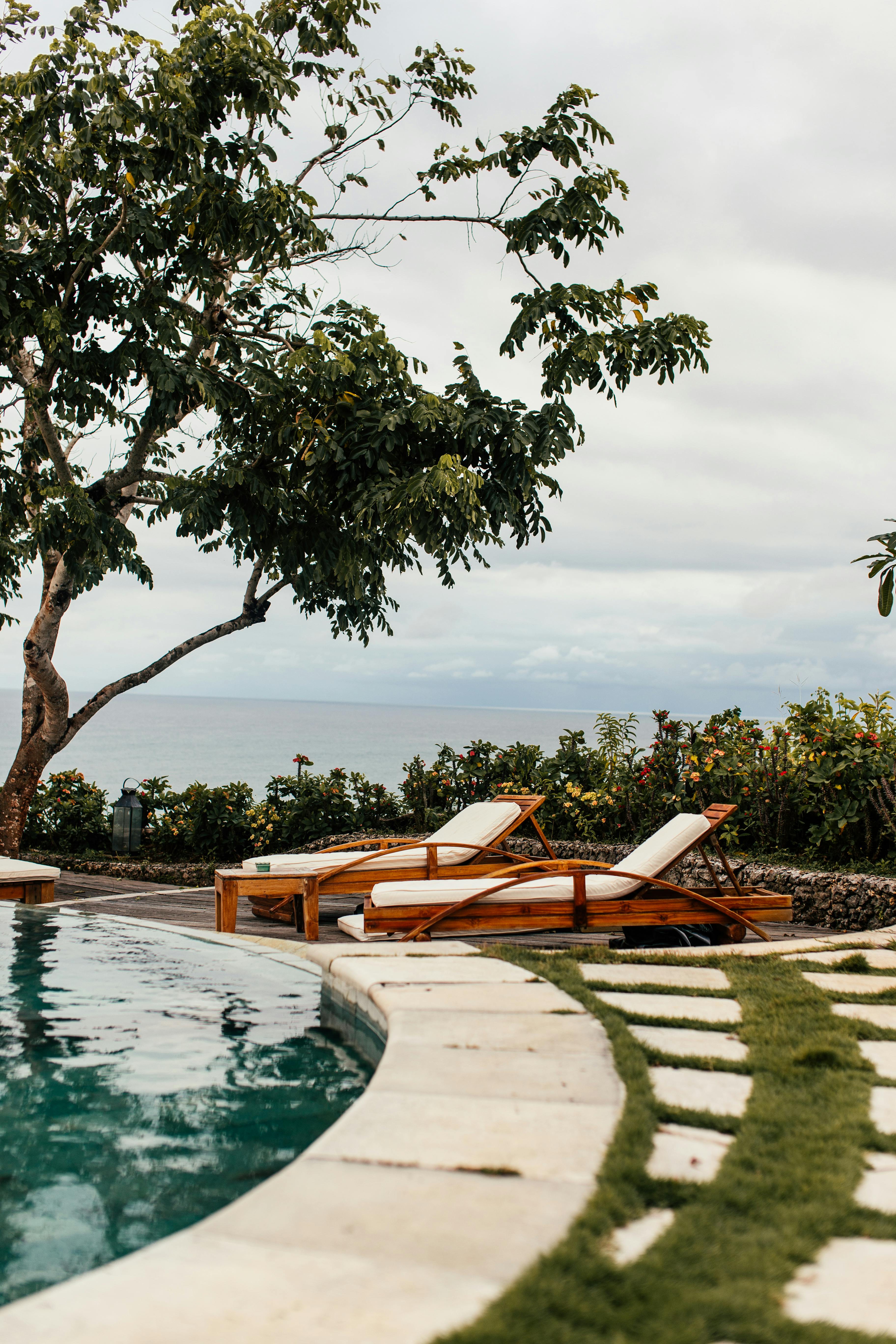 放松的池畔，风景优美的海洋背景、郁郁葱葱的绿化和躺椅，让您享受宁静的休息