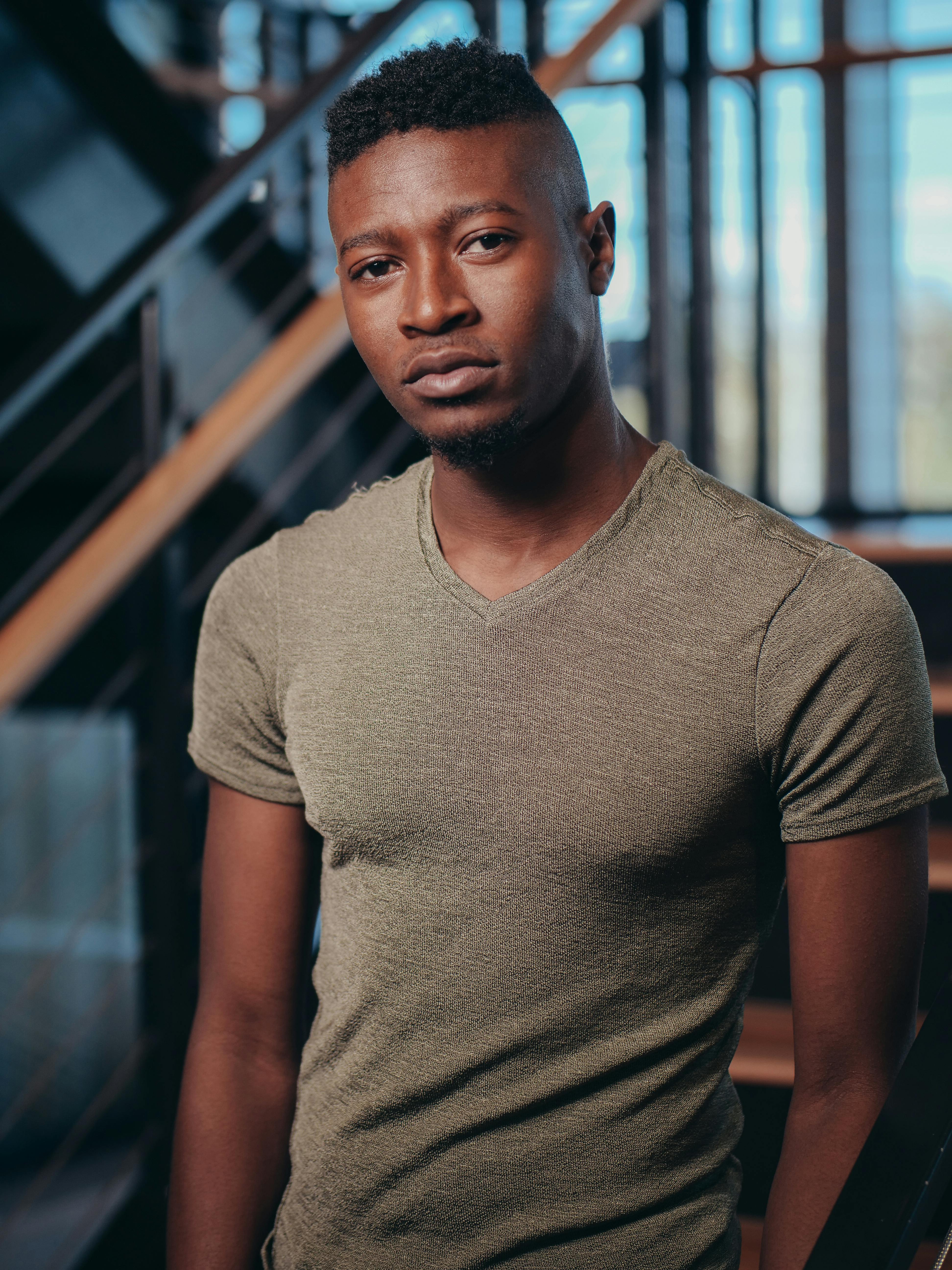 Stylish young man posing indoors with contemporary hairstyle and casual t-shirt.