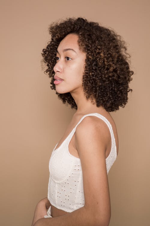 Free Calm female with curly hair against beige background Stock Photo