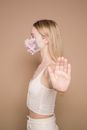 Serious woman in flower mask showing stop gesture