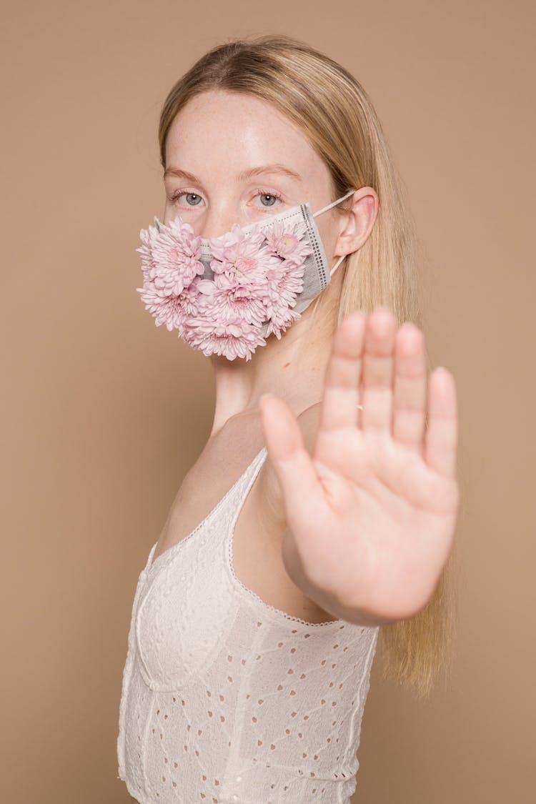 Woman In Flower Mask Showing Hand To Camera