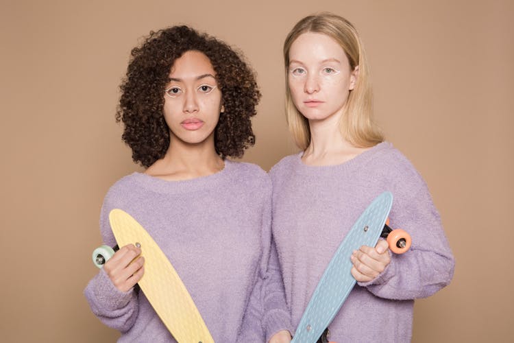 Calm Diverse Women In Similar Clothes With Penny Boards