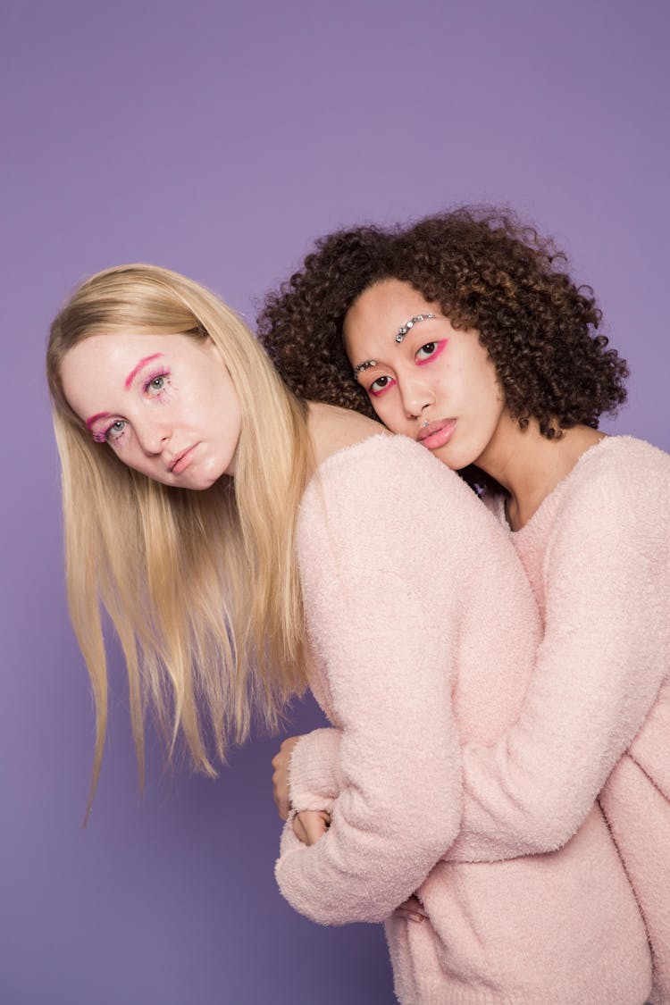 Sad Multiethnic Women With Colorful Makeup Hugging In Studio