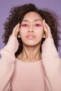 Confident ethnic woman with colorful makeup in studio