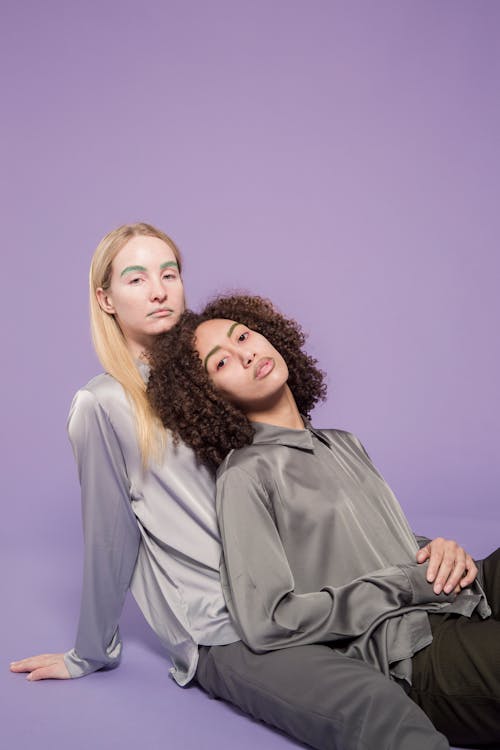 Serious multiracial ladies leaning on each other in studio
