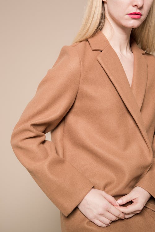 Stylish woman with hands together in trendy beige coat