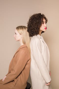 Elegant portrait of two diverse women in stylish outfits on a beige background.