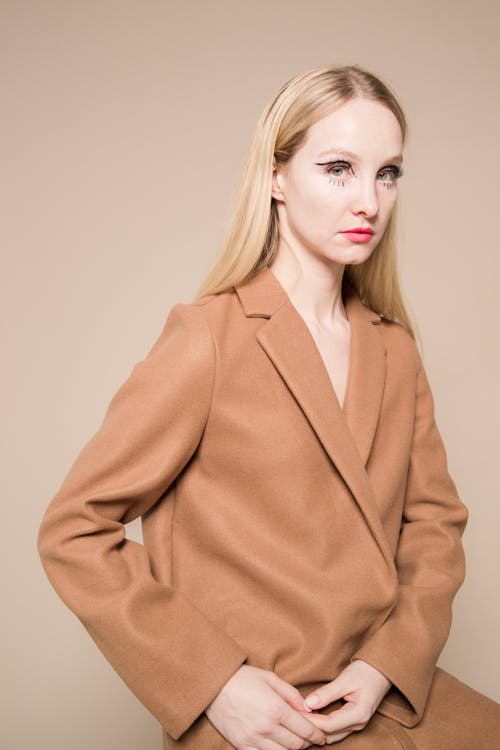 Free Trendy female with extraordinary makeup in fashionable brown coat on beige background Stock Photo