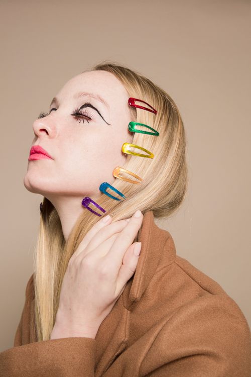 Free Eccentric stylish female with many hair clips and eyes closed on beige background of studio Stock Photo