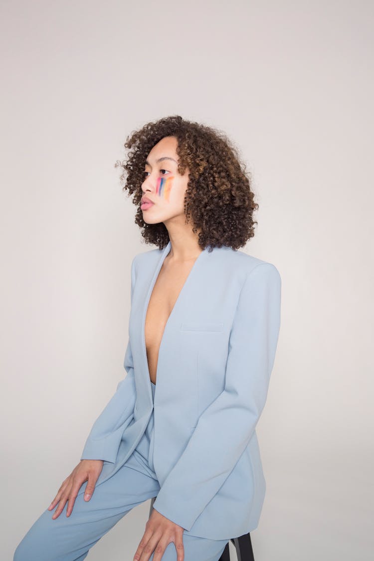 Trendy Woman With Creative Makeup In Suit Looking Away In Studio