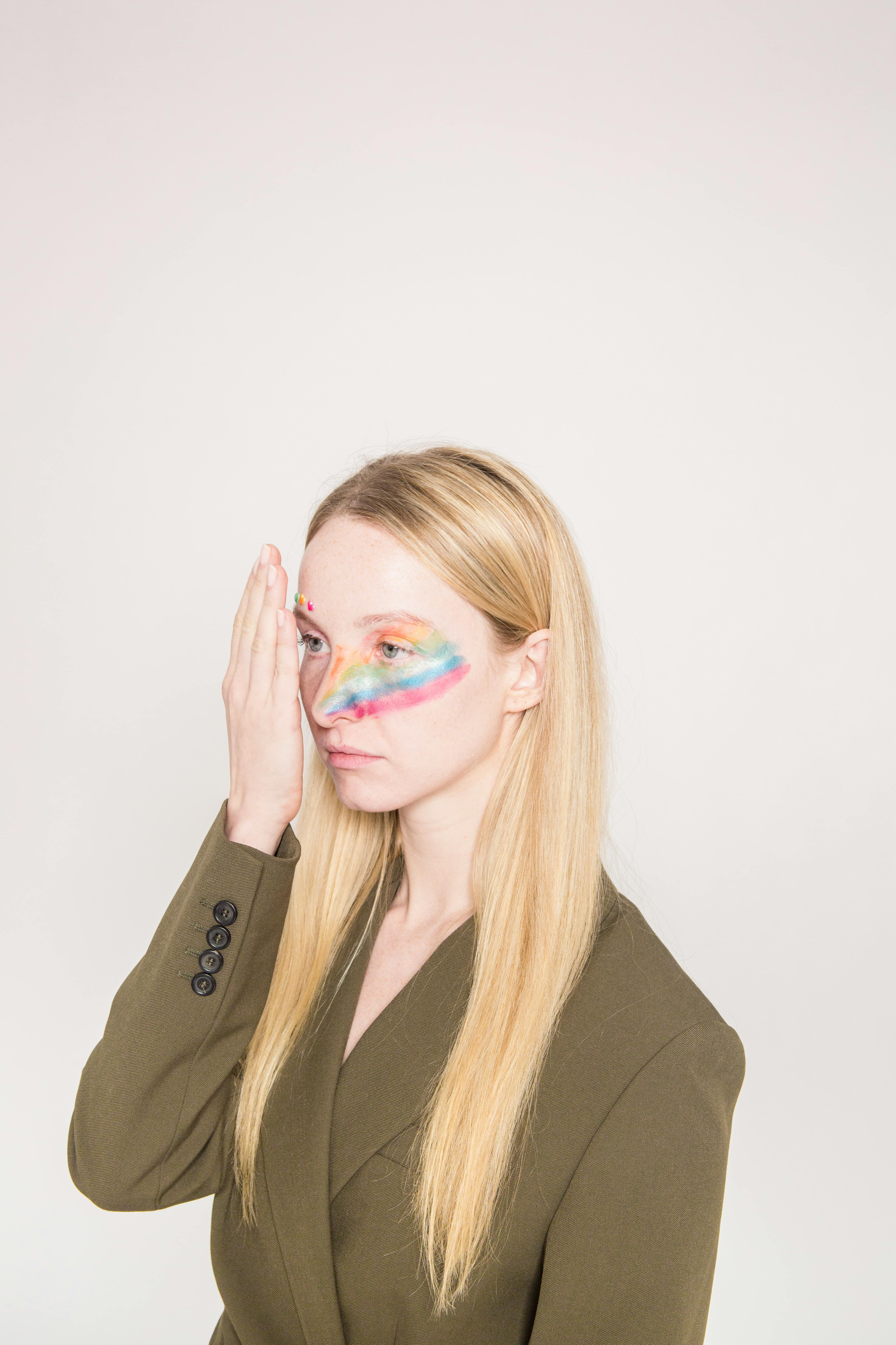 serious woman with painted face looking away against beige wall