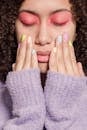 Thoughtful ethnic woman touching face with hands with pastel nails